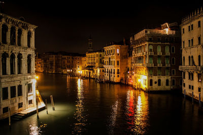 Canal amidst illuminated buildings in city at night