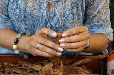 Midsection of woman making cigar