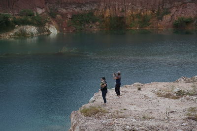 People on rock by lake