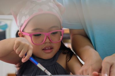 Close-up of hand helping girl preparing food on table