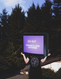 Low section of woman holding text by tree against plants