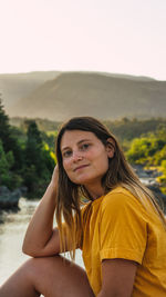 Portrait of beautiful young woman sitting on land