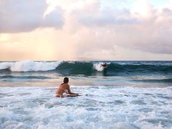 People surfing in sea against sky