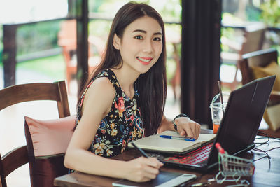 Portrait of smiling woman working with technologies while sitting on chair