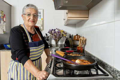 Old lady in the kitchen cooking food.