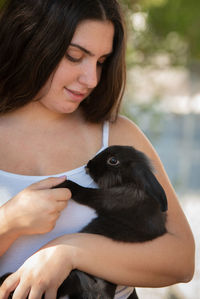 Young beautiful woman holding a black rabbit pet animal. domestic animal caring