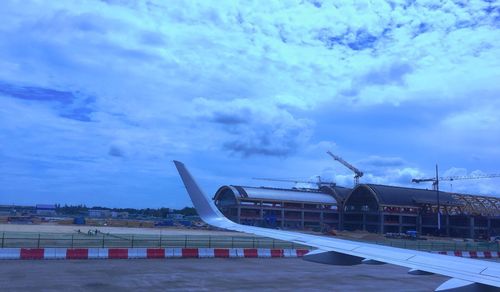 Airplane on airport runway against sky in city