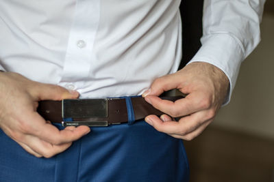 Midsection of man adjusting belt