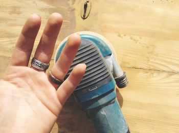 Man showing his hand with sander on wood material