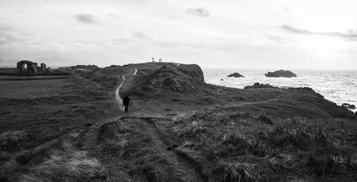 People on rocks by sea against sky