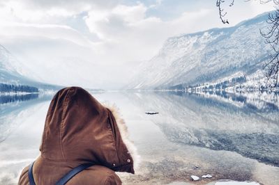 Rear view of woman by lake and snow covered mountains against sky