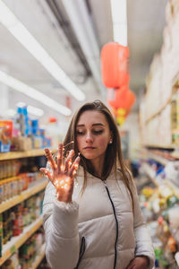 Young woman holding illuminated string light in supermarket