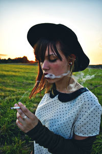 Close-up of young wearing hat while smoking on field