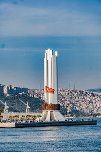 Sailboat on sea by buildings against sky in city