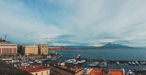 City at waterfront against cloudy sky