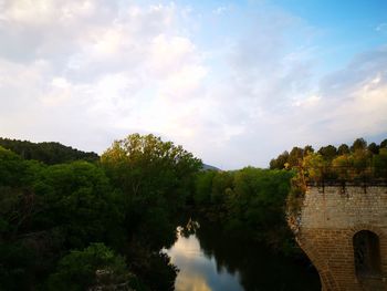 Arch bridge over river against cloudy sky