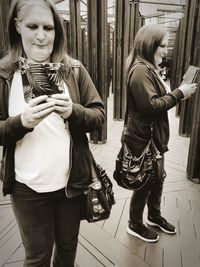 Mature woman holding mobile phone while standing in mirror maze