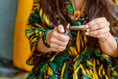 A stick of palo santo tree in the hands of a girl. a woman lights a stick. close up.