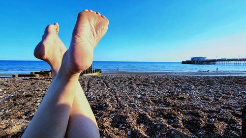 Low section of person on beach against sky
