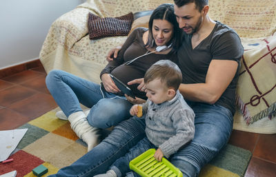 Parents with son using digital tablet while sitting in living room at home