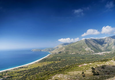 Scenic view of sea and mountains against blue sky