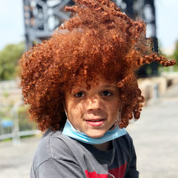 Portrait of cute smiling boy with red hair outdoors