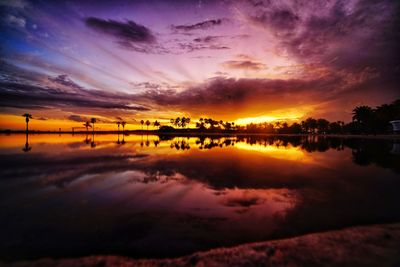 Scenic view of lake against dramatic sky during sunset