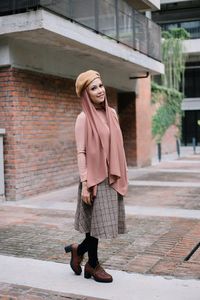 Full length portrait of woman standing on footpath