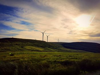 Windmill on field against sky during sunset