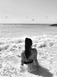 Rear view of woman sitting on beach