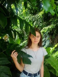 Portrait of young woman standing by leaves