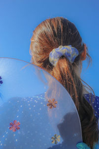 Rear view of woman against blue sky
