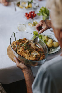 Woman's hands holding glass dish with meat