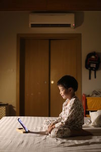 Side view of boy using laptop while sitting at home