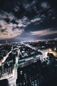 Illuminated cityscape against cloudy sky