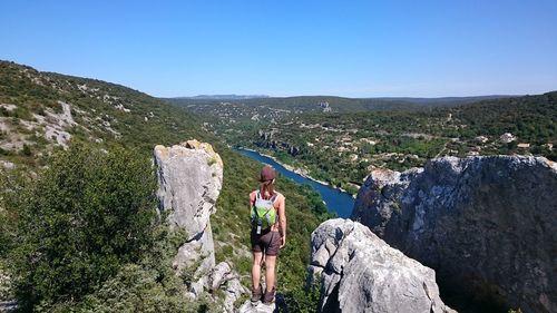 Man standing on rock against sky