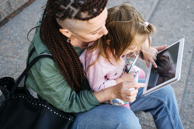 Freelance parents. busy working mom with baby toddler daughter on hands walk and looking on tablet