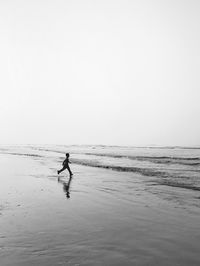 Man on beach against clear sky