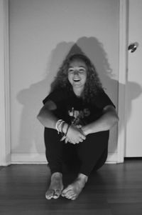 Portrait of a smiling young woman sitting on floor at home