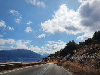 Empty road along landscape and mountains against sky