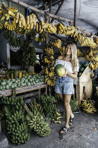 Full length of smiling woman standing at market stall