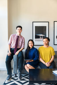 Portrait of confident male and female business colleagues sitting on sofa at office