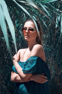 Portrait of young woman wearing sunglasses standing on field