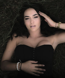 Close portrait of a brunette woman, with brown eyes, long hair, lying in the grass. upper view. 