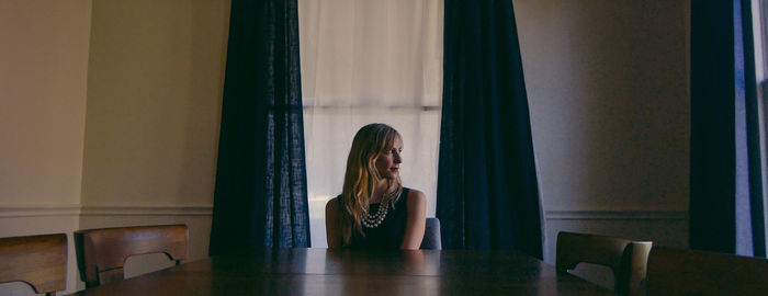 Thoughtful woman looking away while sitting at home