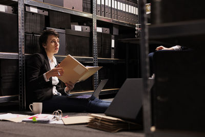 Rear view of woman using laptop while sitting on table