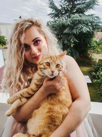 Portrait of young woman with cat sitting outdoors