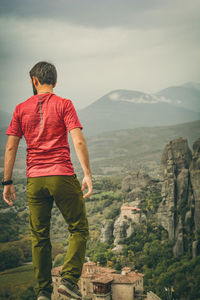 Rear view of man looking at mountains against sky