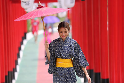 Woman holding umbrella standing outdoors in temple