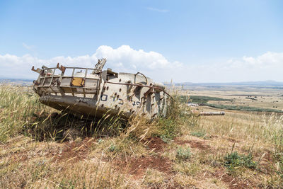 Abandoned ship on field against sky